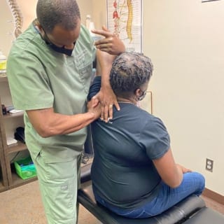 Dr. Jeremy putting pressure on a patient's shoulder.